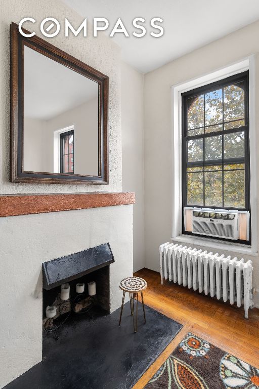 sitting room featuring cooling unit, radiator, and hardwood / wood-style floors