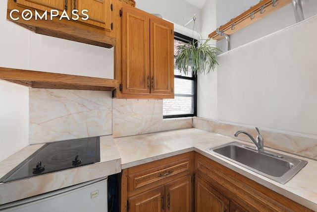 kitchen featuring black electric stovetop, sink, and decorative backsplash