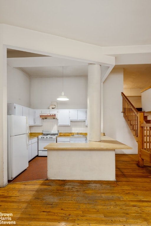 kitchen with white cabinetry, kitchen peninsula, hanging light fixtures, light hardwood / wood-style flooring, and white appliances