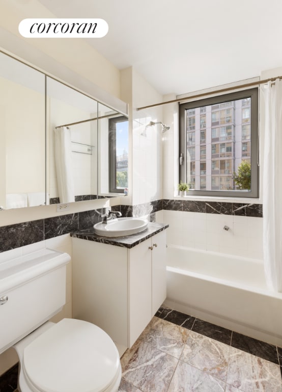 full bathroom featuring shower / bath combination with curtain, vanity, toilet, and a healthy amount of sunlight