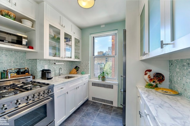 kitchen with sink, light stone countertops, stainless steel appliances, white cabinets, and radiator heating unit