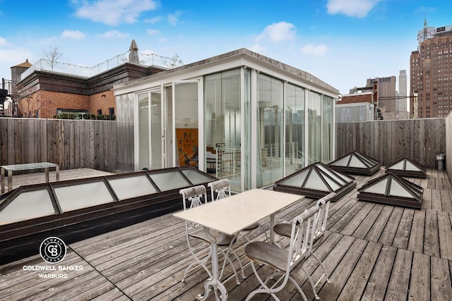 wooden deck with a sunroom, a view of city, and fence