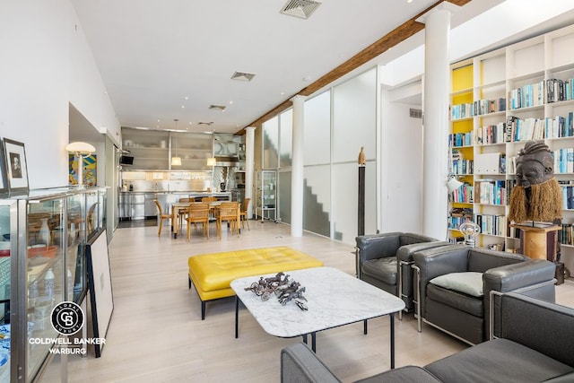 living area featuring stairway, decorative columns, visible vents, and light wood-style floors