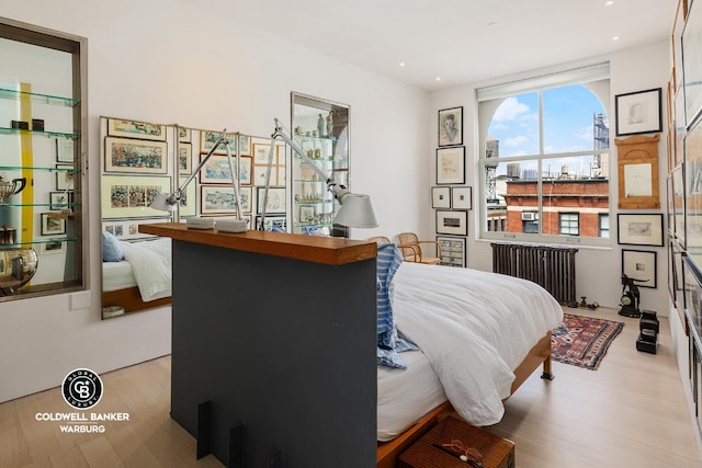 bedroom with light wood-style floors, recessed lighting, and radiator