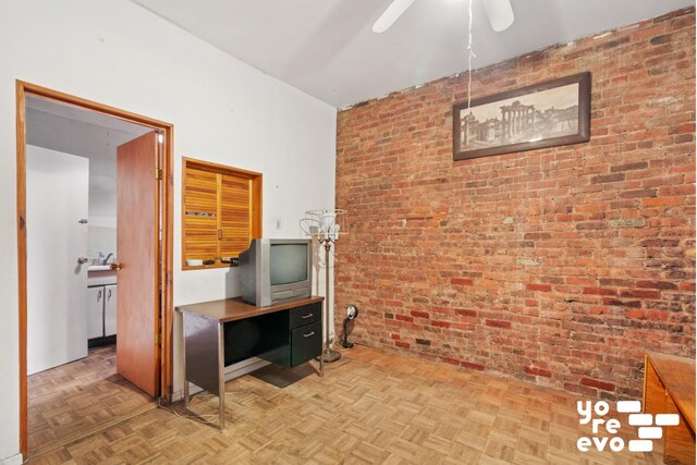 office area with ceiling fan, parquet floors, and brick wall