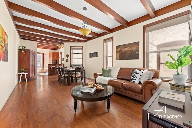 living area with beamed ceiling, wood finished floors, and baseboards