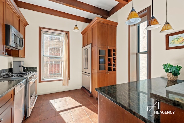210 W 85th St Unit 5W, New York City, NY 10024 - kitchen with stainless steel appliances, brown cabinets, tile patterned flooring, beam ceiling, and dark stone countertops