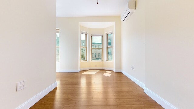 563 W 182nd St, New York City, NY 10033 - empty room with a wall unit AC, hardwood / wood-style flooring, and baseboards