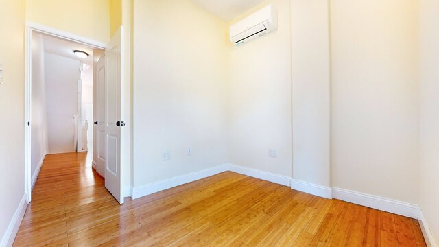 unfurnished room featuring hardwood / wood-style flooring, ceiling fan, and an AC wall unit