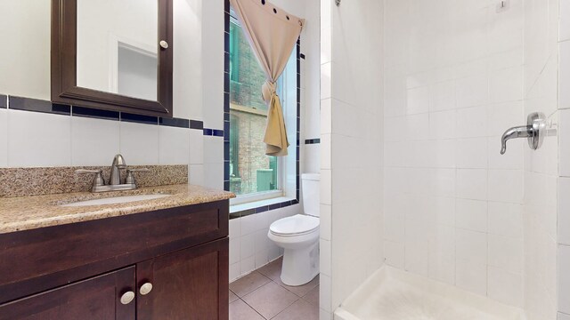 full bathroom featuring tile walls, shower / bath combination with glass door, tile patterned flooring, vanity, and toilet