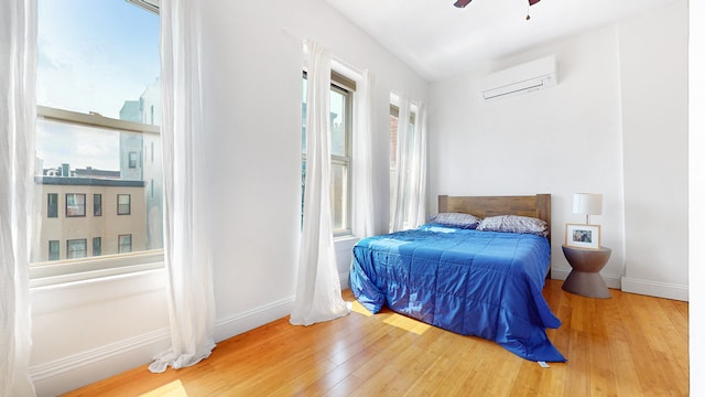 563 W 182nd St, New York City, NY 10033 - bedroom featuring a wall mounted AC, hardwood / wood-style flooring, baseboards, and a ceiling fan