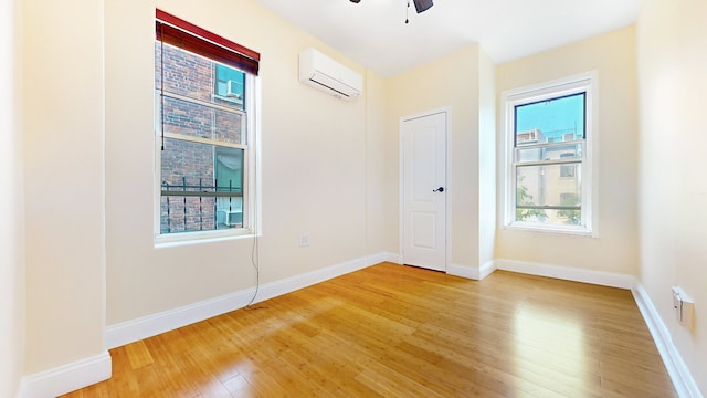 563 W 182nd St, New York City, NY 10033 - unfurnished bedroom with a wall mounted AC, multiple windows, and light wood-type flooring
