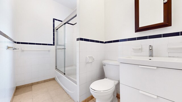 563 W 182nd St, New York City, NY 10033 - bathroom featuring tile walls, toilet, vanity, a wainscoted wall, and enclosed tub / shower combo