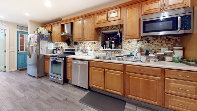 563 W 182nd St, New York City, NY 10033 - kitchen with stainless steel appliances, a sink, wall chimney range hood, backsplash, and light countertops