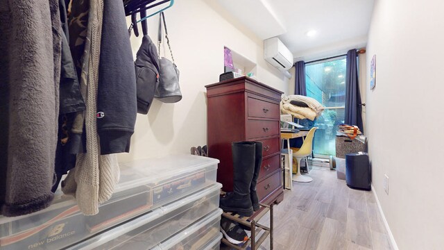 living room with wood-type flooring, ceiling fan with notable chandelier, and a wall mounted air conditioner