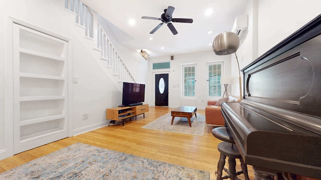 563 W 182nd St, New York City, NY 10033 - living room with a wall mounted AC, hardwood / wood-style flooring, ceiling fan, stairs, and baseboards