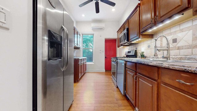 unfurnished room featuring ceiling fan, a wall mounted AC, and light wood-type flooring