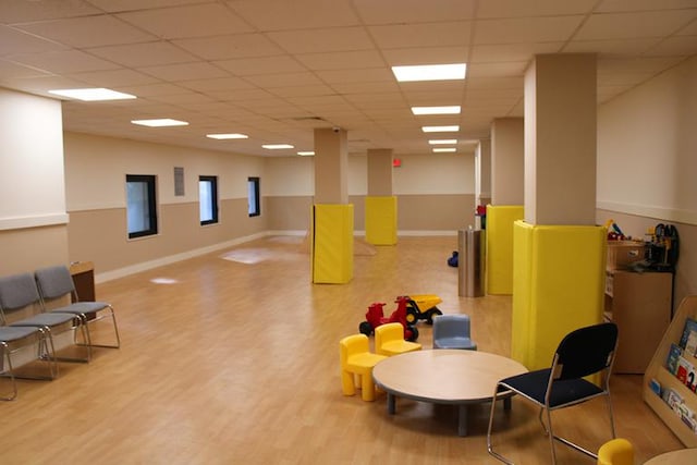 playroom featuring a paneled ceiling, baseboards, and wood finished floors