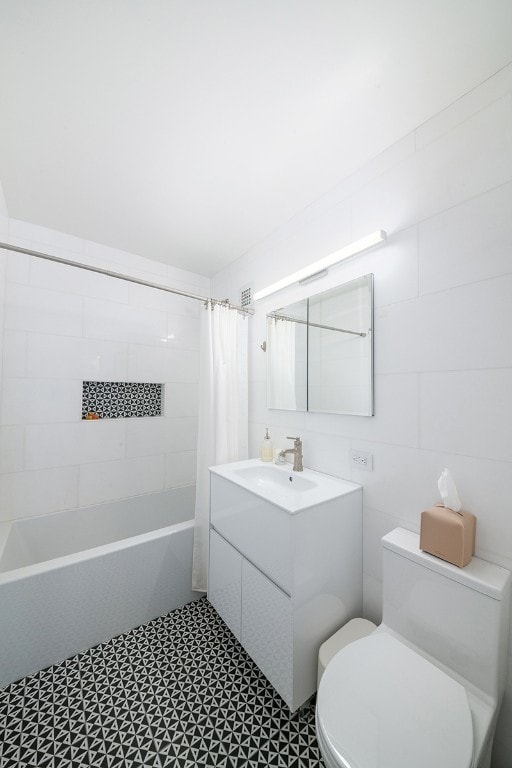 full bathroom featuring toilet, tile patterned floors, shower / bathtub combination with curtain, vanity, and tile walls