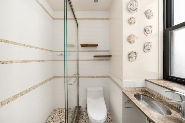 bathroom featuring sink, tile walls, toilet, and a shower with door