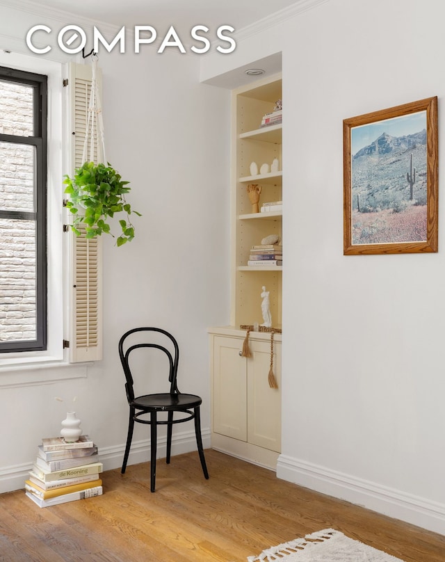 living area featuring baseboards, built in shelves, and light wood-style floors