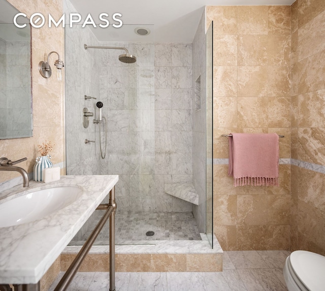 full bathroom with vanity, walk in shower, toilet, and tile walls