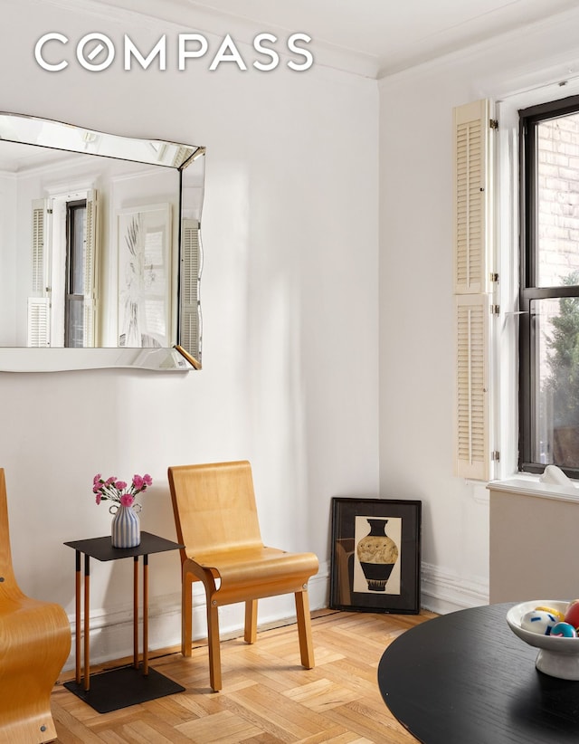 living area featuring baseboards and crown molding