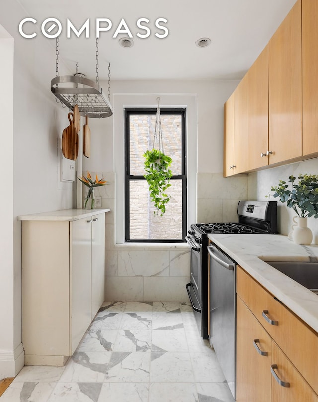 kitchen with stainless steel appliances, marble finish floor, and light stone counters