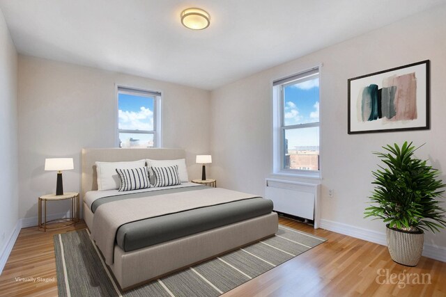 bedroom featuring light wood finished floors, radiator heating unit, and baseboards