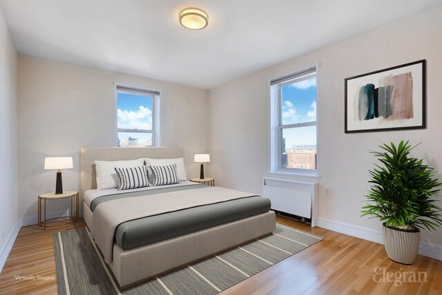 bedroom featuring light wood-style floors, radiator heating unit, and baseboards