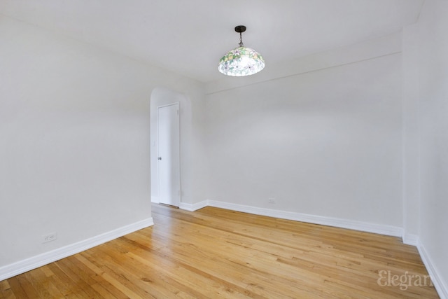 spare room with baseboards and light wood finished floors