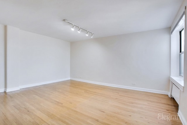 spare room with light hardwood / wood-style floors and track lighting