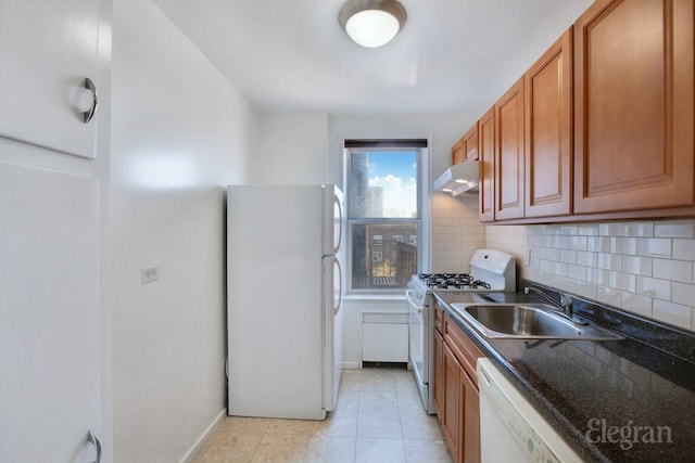 kitchen featuring white appliances, a sink, under cabinet range hood, and backsplash