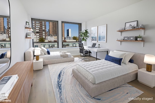 bedroom with a wall of windows and light hardwood / wood-style flooring