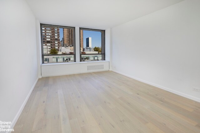 unfurnished room featuring a wall of windows and light hardwood / wood-style floors