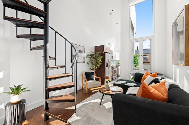 living area featuring a high ceiling, stairway, wood finished floors, and baseboards