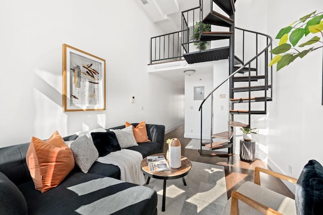 living area with stairway, wood finished floors, a towering ceiling, and baseboards