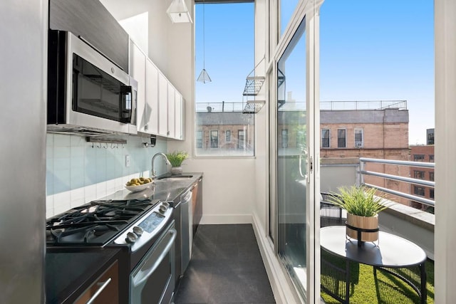 kitchen with a sink, white cabinetry, baseboards, appliances with stainless steel finishes, and tasteful backsplash