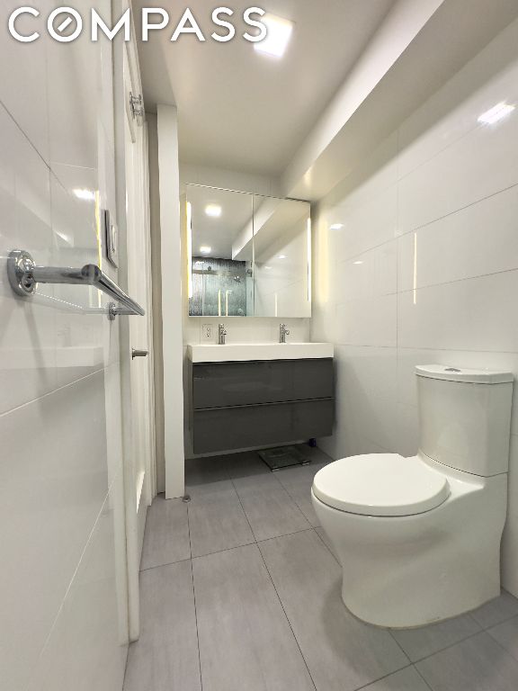 bathroom featuring tile walls, toilet, vanity, and tile patterned flooring