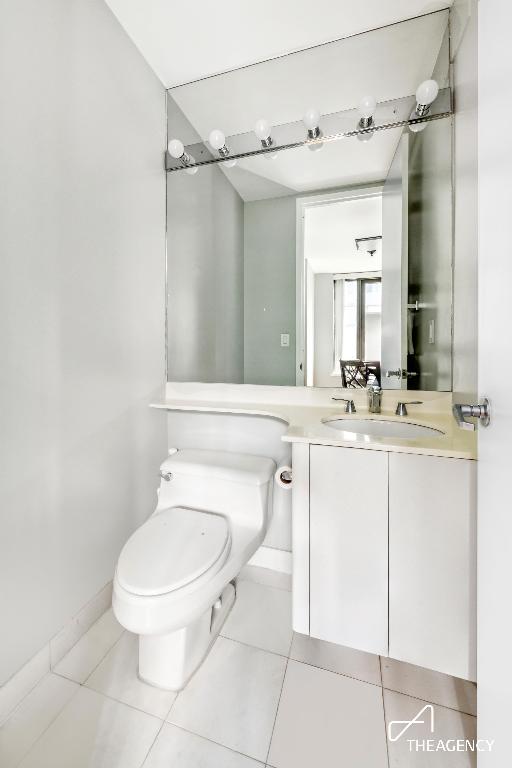 bathroom with toilet, vanity, and tile patterned floors