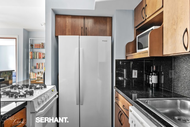 kitchen featuring tasteful backsplash, dark stone countertops, and white appliances