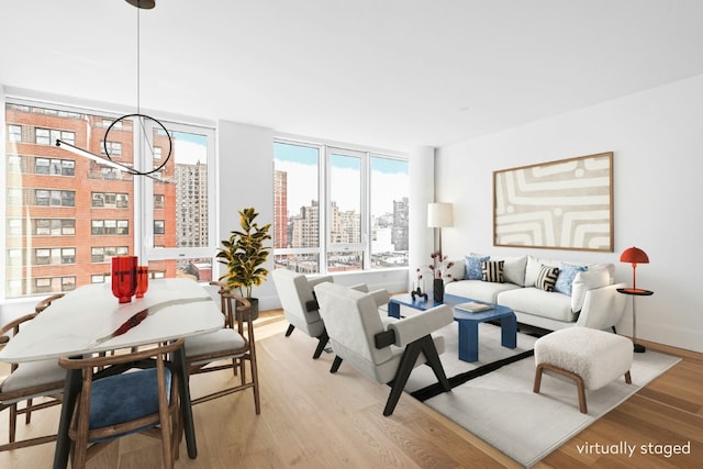 living room with an inviting chandelier, a wall of windows, and light hardwood / wood-style flooring