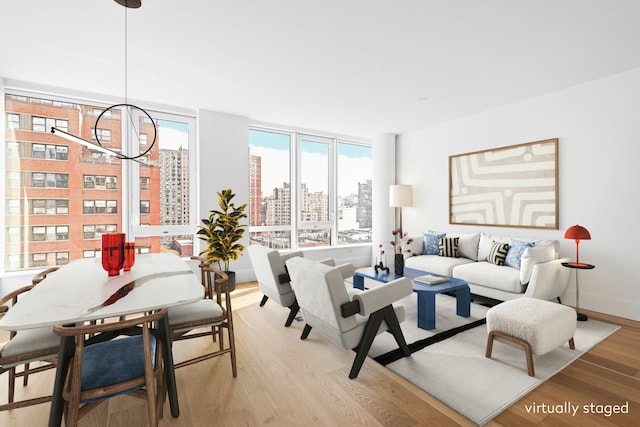 living area with baseboards, expansive windows, a city view, light wood-type flooring, and a notable chandelier