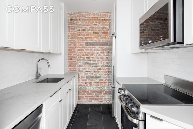 kitchen with light stone countertops, white cabinetry, appliances with stainless steel finishes, and a sink