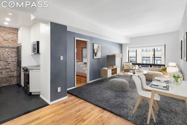 living room with brick wall and hardwood / wood-style floors