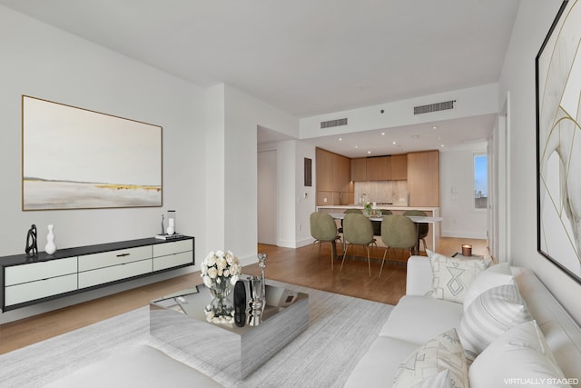 living area with baseboards, visible vents, and light wood-style floors