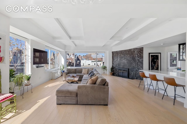 living room featuring beam ceiling, a fireplace, baseboards, and wood finished floors