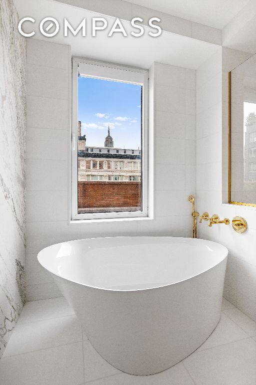 bathroom with a washtub, tile patterned flooring, and tile walls