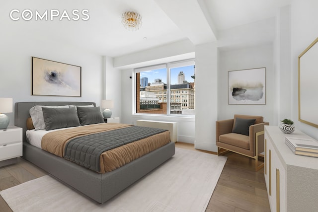 bedroom with light wood-type flooring and a city view