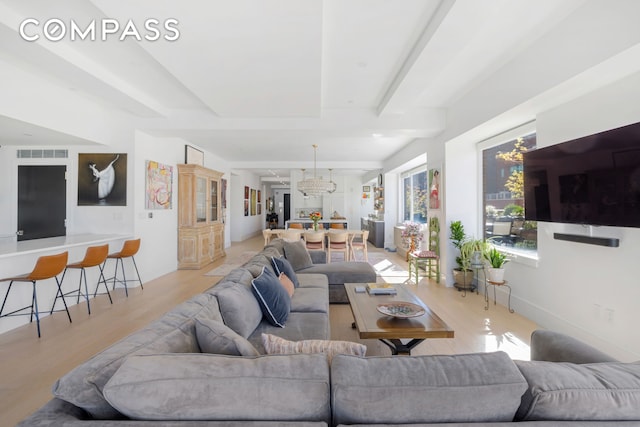 living area featuring visible vents, beamed ceiling, and light wood finished floors